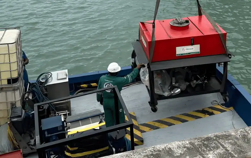 Técnico realiza flushing em sistema hidráulico industrial com mangueiras e painel de controle