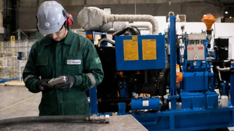 Técnico inspeciona bico de retrolavagem diante de máquina azul de hidrojateamento sem marcas de terceiros